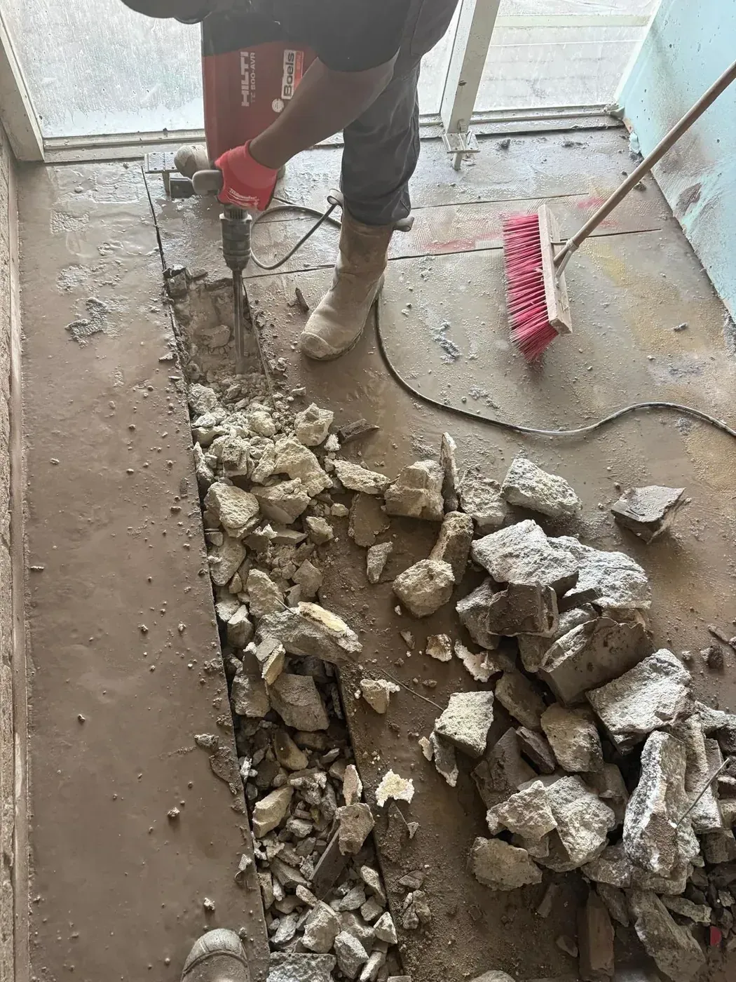 Medewerker met Hilti hamer breekt betonvloer — grote puinhoop actieshot