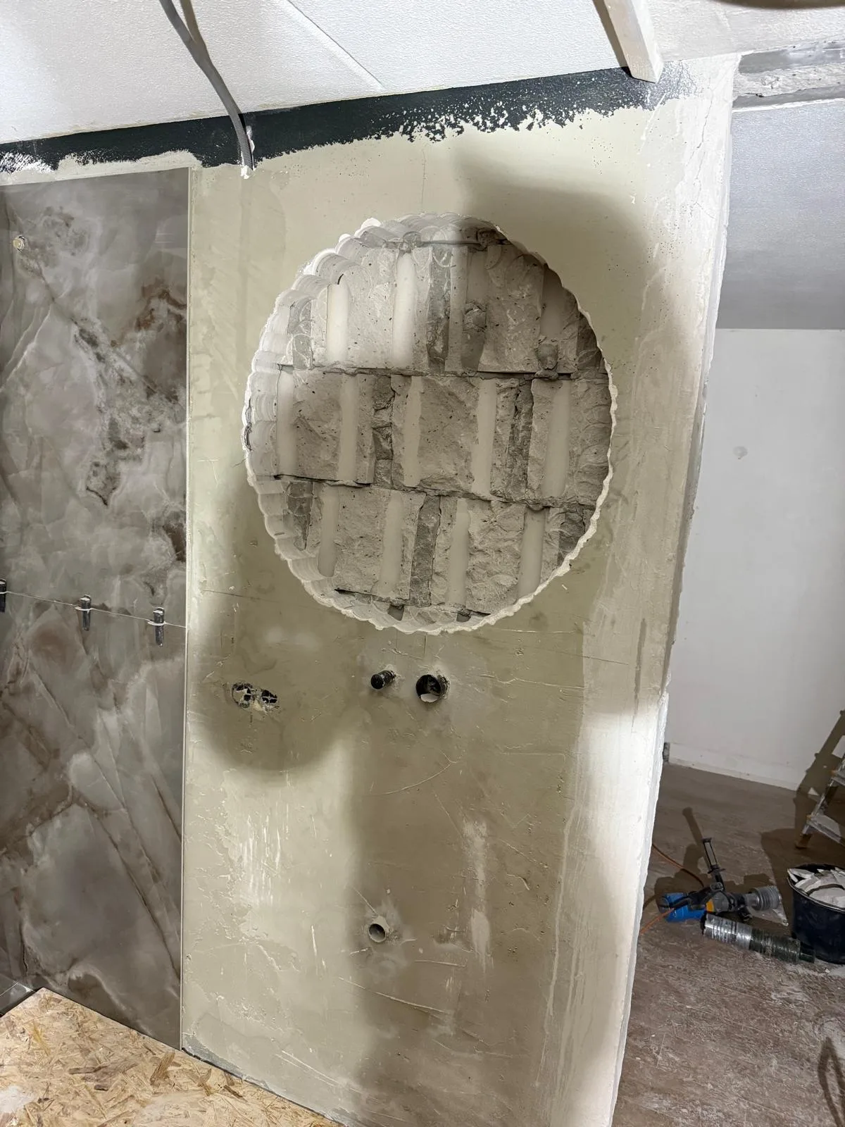 Grote ronde opening doorgebroken in bepleisterde muur badkamer renovatie