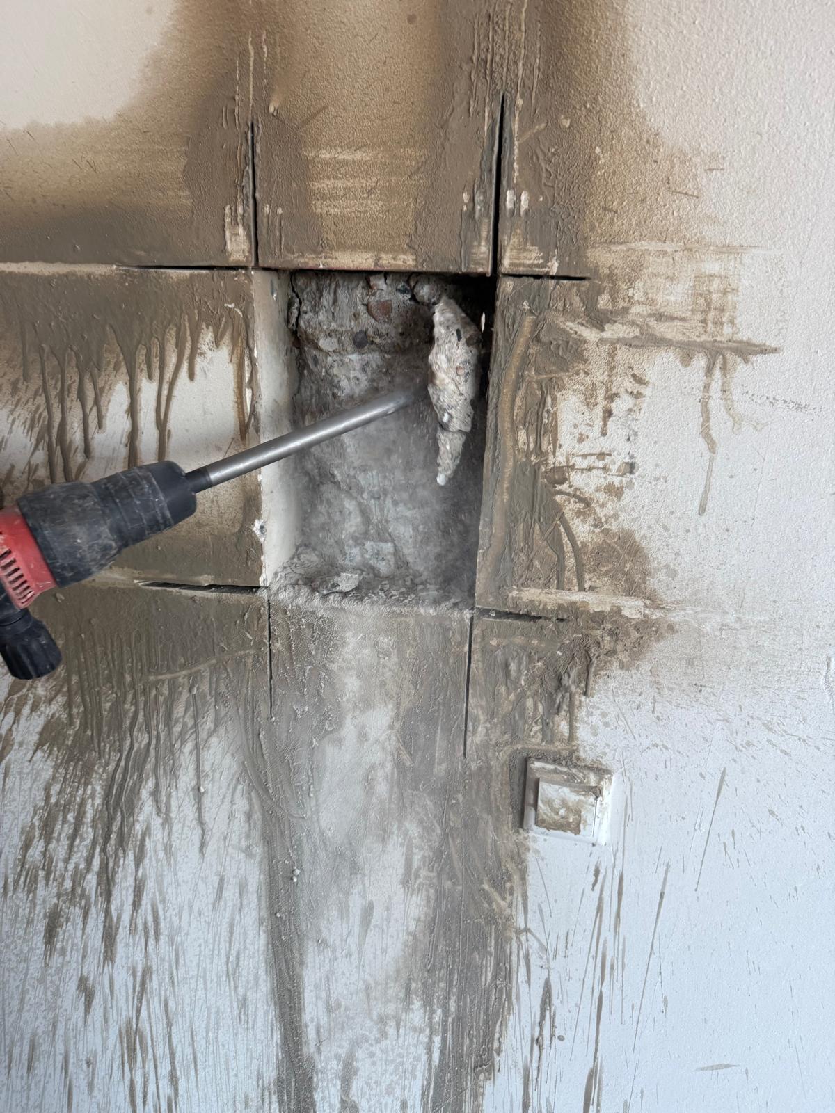 Rode sloophamer breekt opening door betegelde muur actieshot
