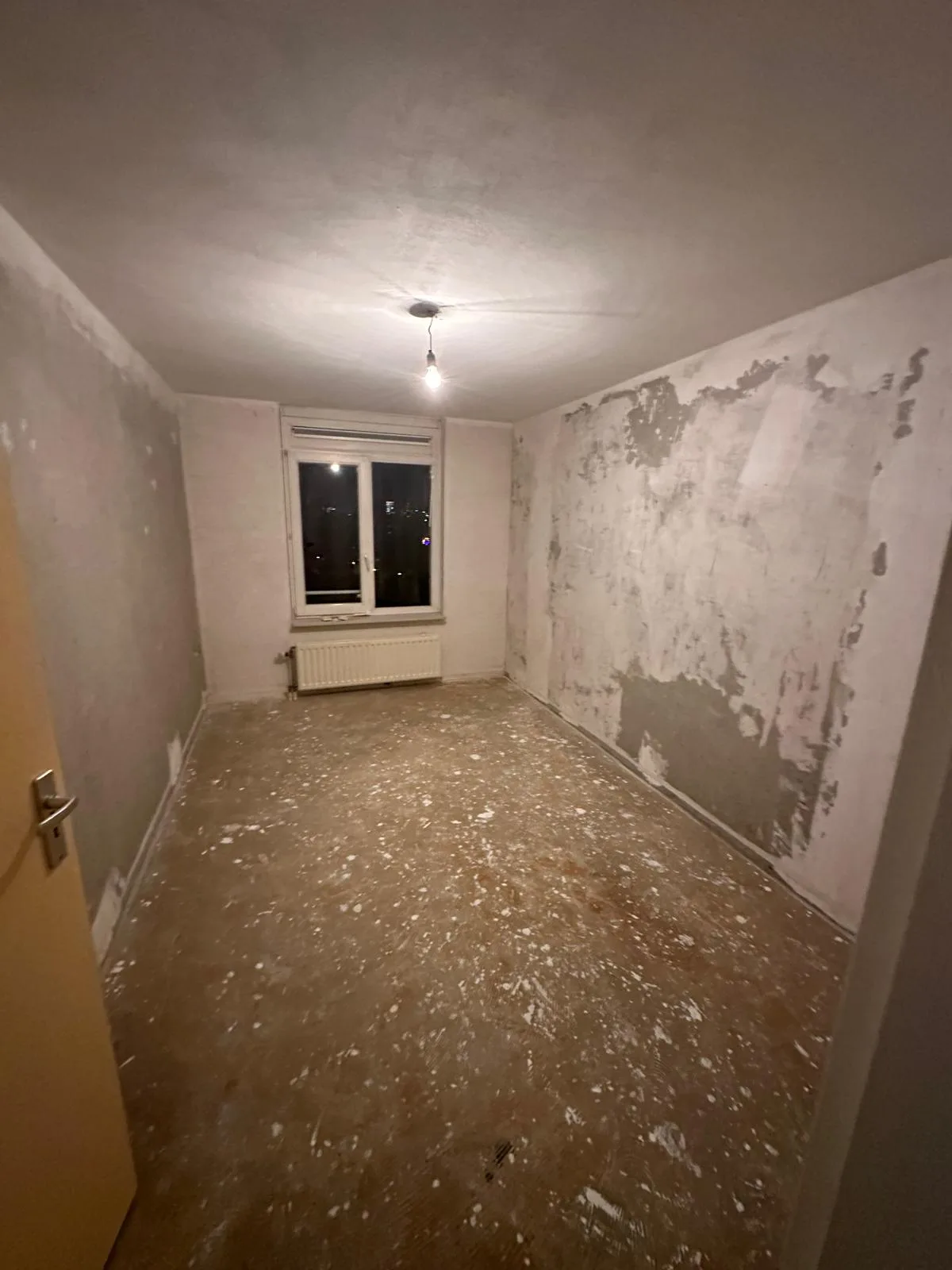 Volledig gestripte kamer — behang en vloer verwijderd, kaal opgeleverd voor renovatie