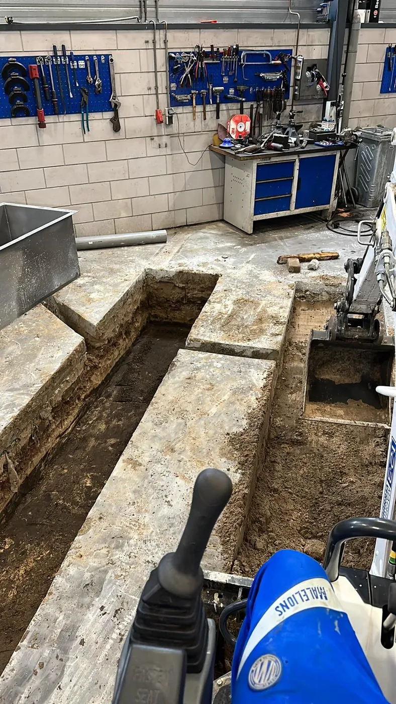Minigraver Naelions graaft sleuven in betonvloer werkplaats — overzicht