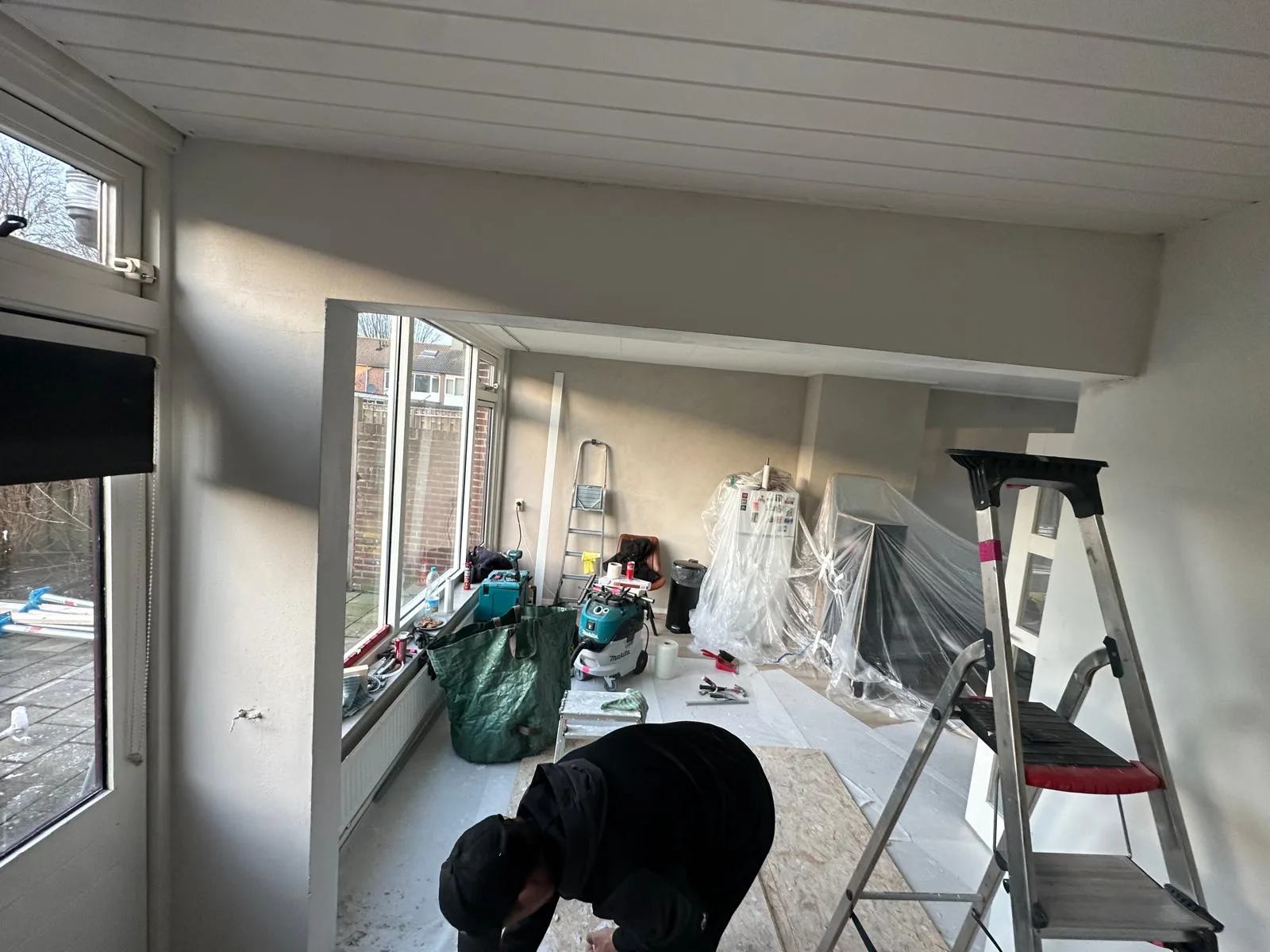 Serre open gemaakt — wand gesloopt, medewerker werkt aan afwerking boog opening