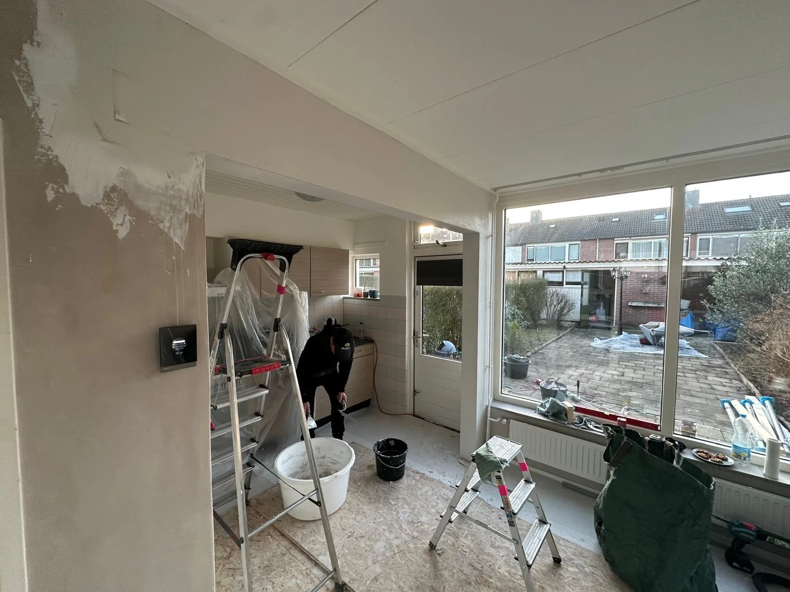 Keuken doorbraak in uitvoering — medewerker werkt aan open verbinding woonkamer keuken