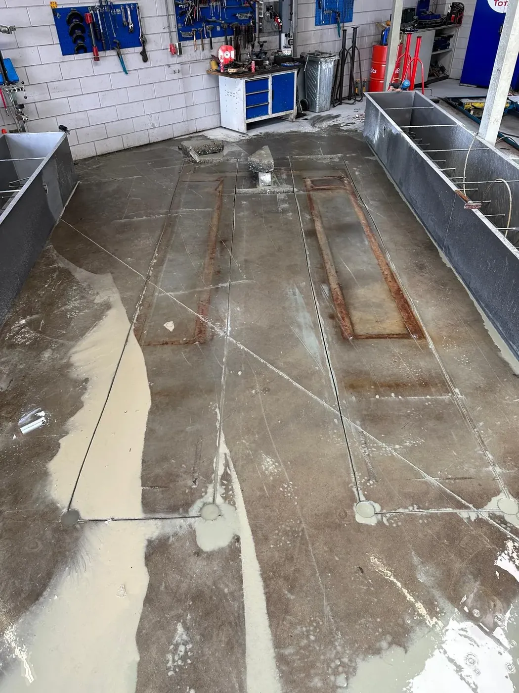 Rechthoekige zaagsneden in garagevloer met zichtbaar wapeningsstaal