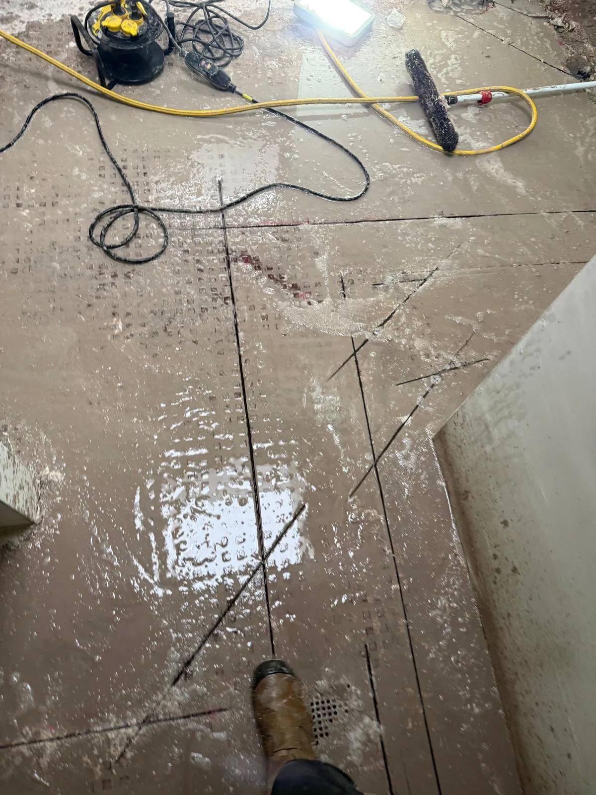 Natte betonvloer met kruissneden en stofzuiger actie zaagwerk